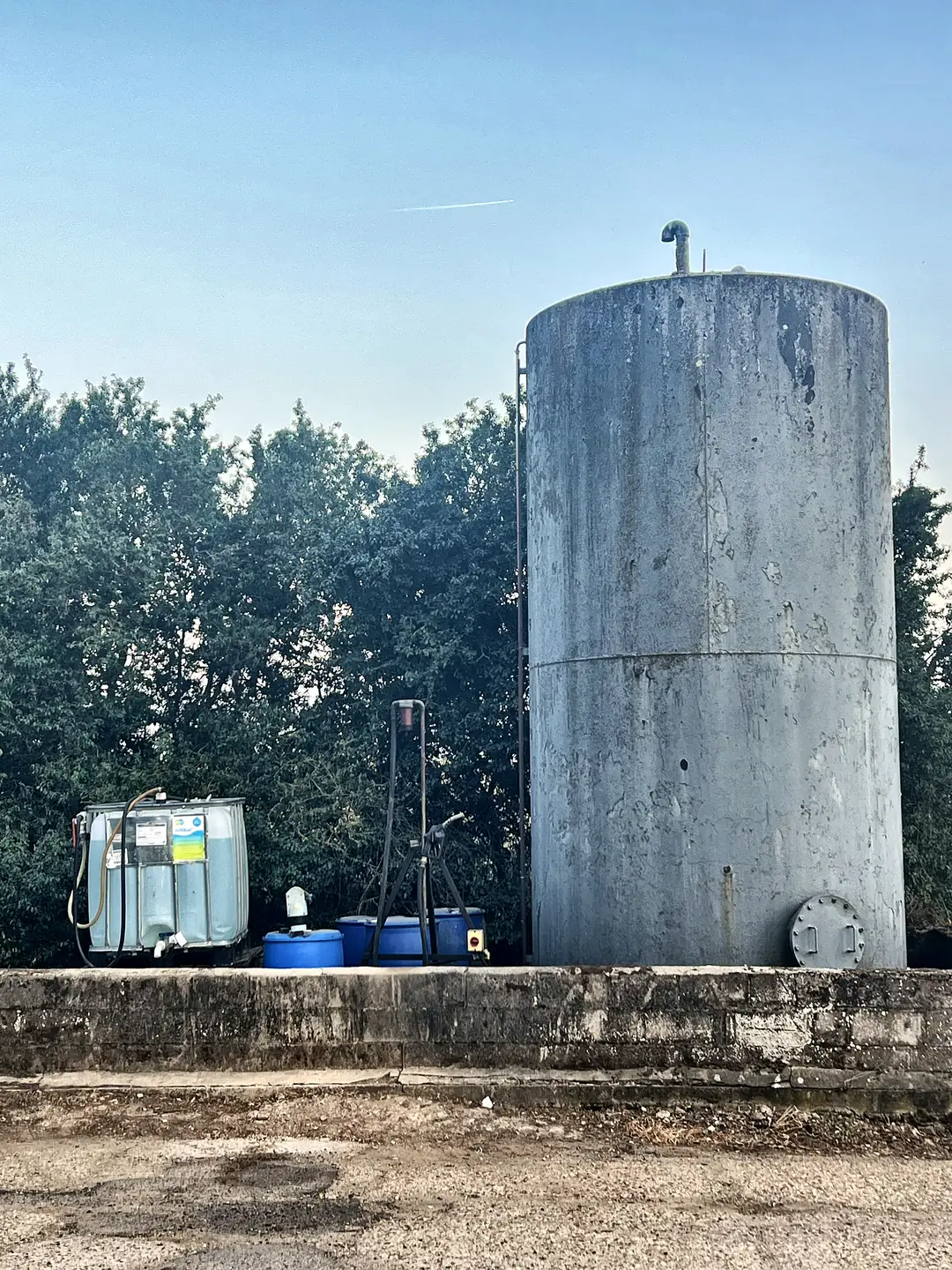 A farm fuel depot with a large diesel storage tank and dispensing pump, guarded by a single CCTV camera