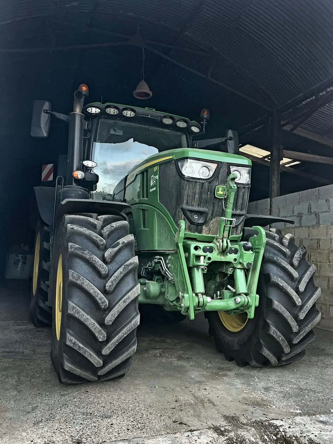 Front view of a modern tractor in a farm barn, its premium rear tyres worth thousands of pounds a pair